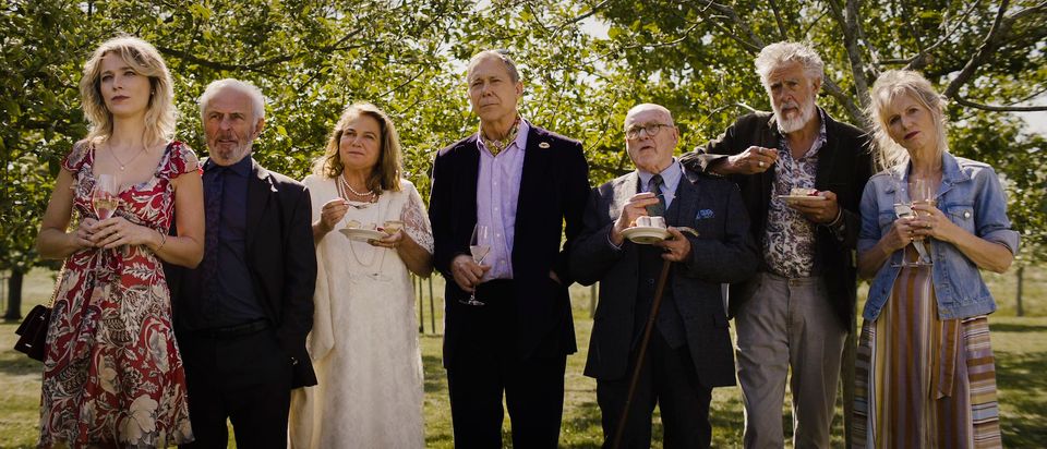 Een groep mensen in nette kleding met taart en champagne