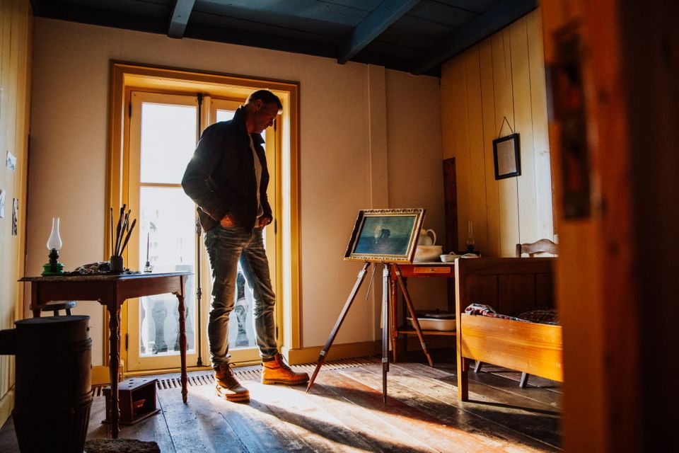Een man bekijkt een schilderij van Van Gogh dat op een schildersezel in de kamer van Van Gogh in het Van Gogh huis staat.