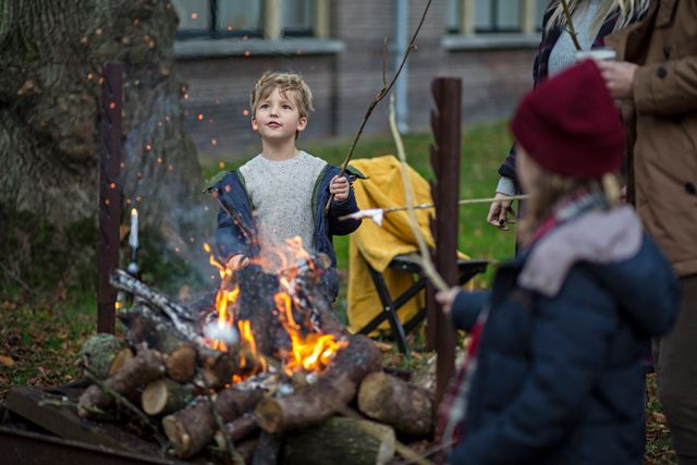 Een jongen en meisje roosteren marshmallows boven het kampvuur op een koude winterdag.