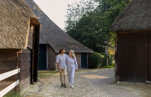 Een stel wandelt in Orvelte tussen de boerderijen door.