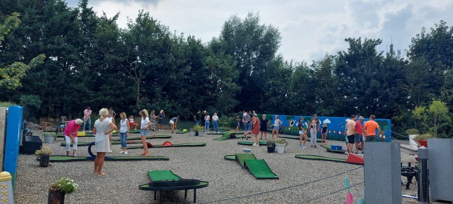 Midgetgolfbaan Boer Hans in Montfoort, Groene Hart, groepsactiviteit in de buitenlucht met mensen die samen midgetgolf spelen op een speels aangelegd terrein tussen groen en bomen.