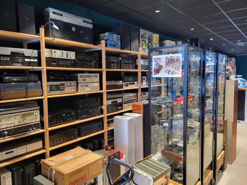 Elektronicawinkel HiFi Stereo in Woerden, Groene Hart, interieur met rekken vol vintage hifi-apparatuur, versterkers, receivers en speakers, overzicht van audiozaak met geluidsinstallaties.