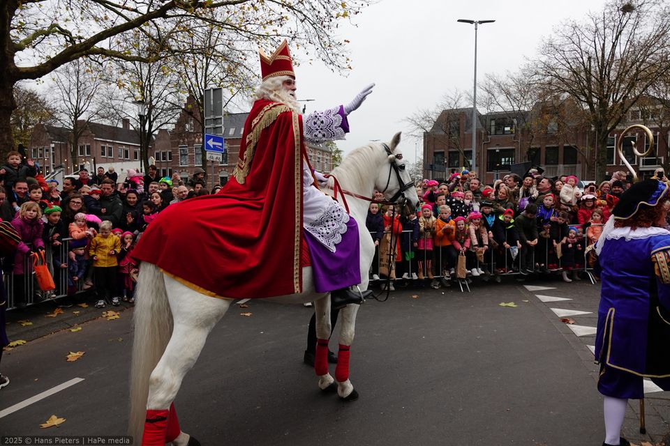 Intocht van Sinterklaas in Woerden, Groene Hart, met Sinterklaas te paard die het publiek begroet tijdens de feestelijke optocht door de stad.