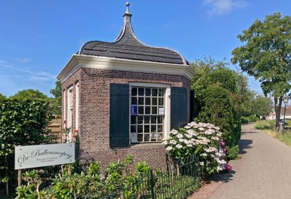 Historisch informatiepunt De Ballensnoeperij Linschoten, Groene Hart, monumentaal bakstenen gebouw met karakteristiek dak, toeristisch informatiepunt en bloeiende hortensia's aan een sfeervolle dorpsstraat.