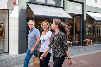 Een man en twee vrouwen zijn aan het winkelen in de winkelstraat van Woerden.