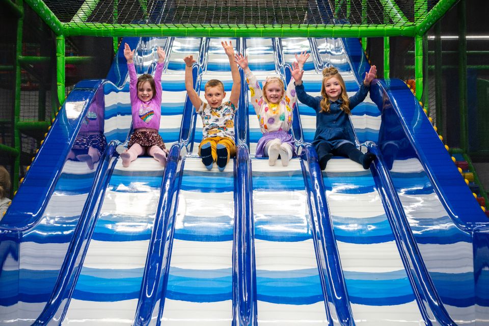 Vier kinderen op rij van glijbaan af.