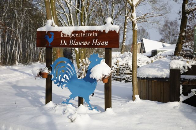 Welkomstbord van een camping in de sneeuw.