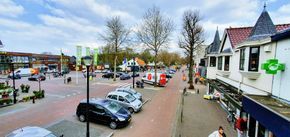 Straatbeeld van het winkelgebied in Soesterberg met winkels, parkeerplaatsen en verkeer. De foto geeft een indruk van het dorpscentrum en de dagelijkse voorzieningen.