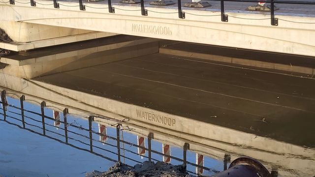 Weerspiegeling van de tekst 'Waterknoop' in het water onder de brug