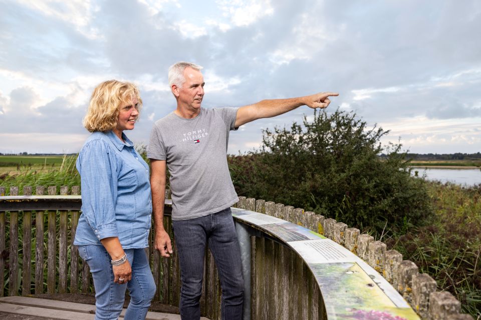 Een man en vrouw kijken vanuit een panoramatafel over natuurgebied Noordpolder in Ossendrecht.
