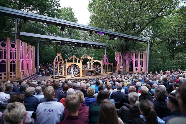 Publikum im Vordergrund und Hintergrund, in der Mitte die Kulisse von Shakespeares Stück.