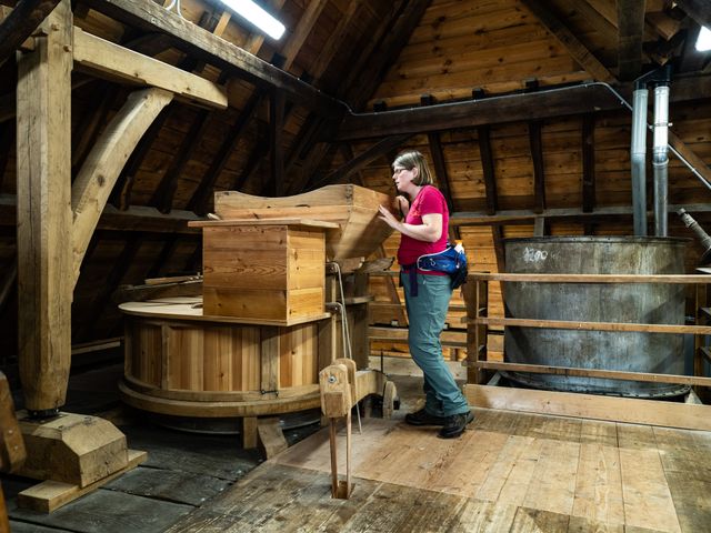 Boswachter Ellen die in de Genneper Watermolen staat te kijken naar een nog werkende korenmolen.