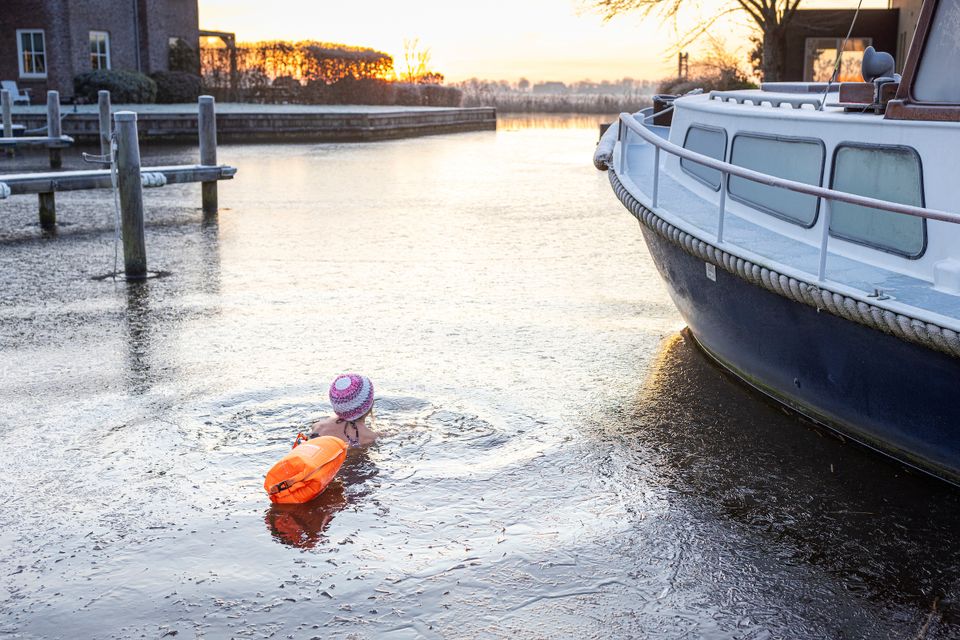 iemand is aan het zwemmen door een dun laagje ijs op het water