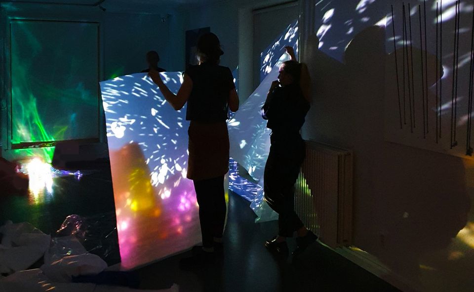 Twee bezoekers genieten van lichtkunst in donkere galerie