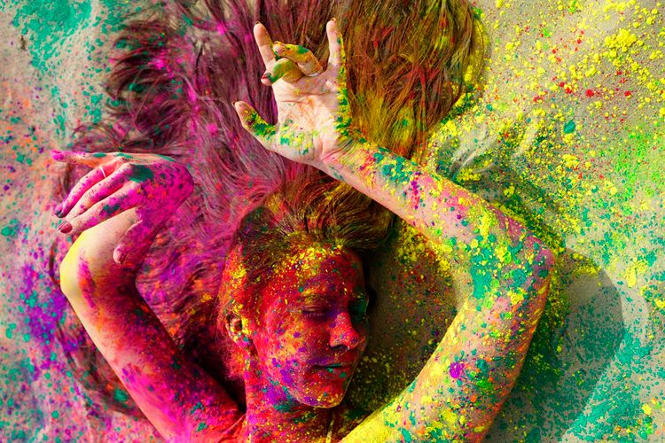 Foto van een vrouw gehuld in allerlei kleuren verfspetters.