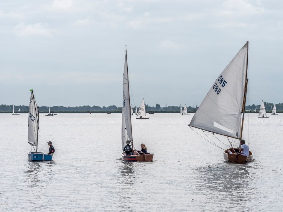 drie zeilbootjes naast elkaar met op de achtergrond nog een groep zeilbootjes