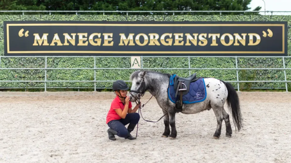 Kind met helm en pony tijdens een paardrijles op de open dag bij Manege Morgenstond in Woerden.