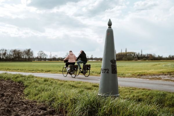 Grenspaal langs de weg met fietsers