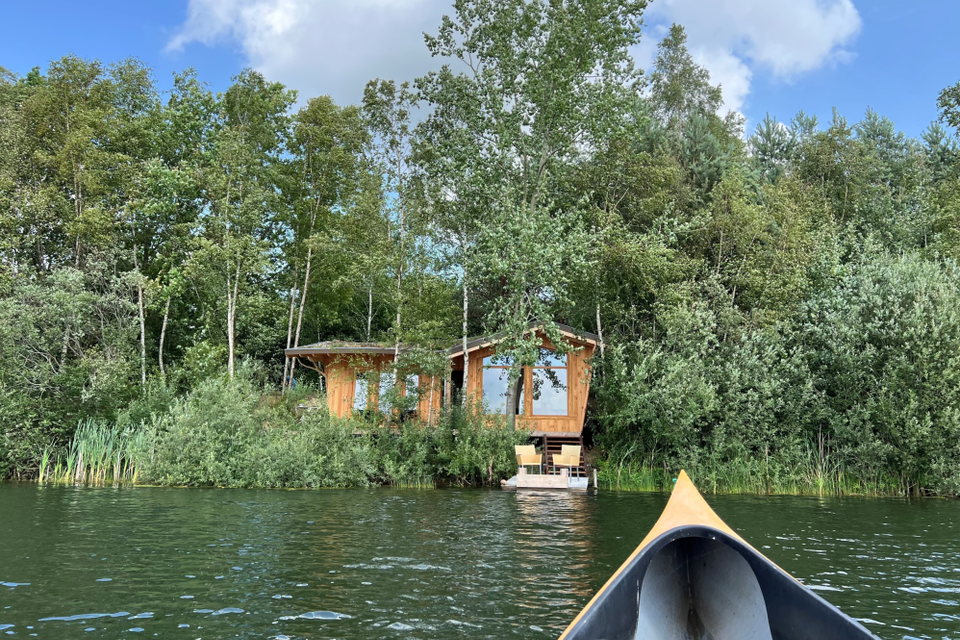 Een houten huisje aan het water met 2 uitnodigende stoelen op de steiger bij Landgoed Hendriksveen.