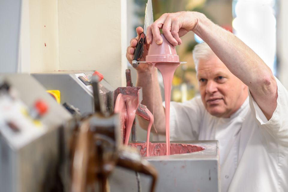 Chocolatier giet vloeibare roze chocolade in de werkplaats van Zuccotto in IJsselstein.