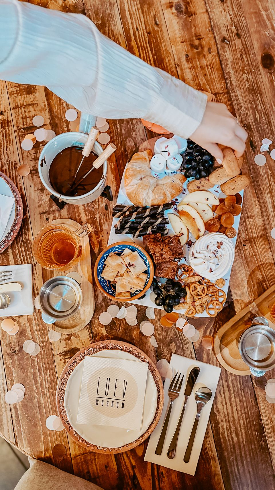 Een chocoladefondue met allerlei hapjes op een plank en een hand die grijpt naar een Frysk dumke bij Loev in Workum.