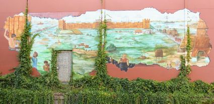 Een indrukwekkende muurschildering die de Romeinse geschiedenis van Woerden tot leven brengt. Te midden van klimop en verweerde muren ontvouwt zich een levendig tafereel van het castellum, het omliggende landschap en het dagelijkse leven langs de Limes. De schildering vormt een kleurrijke ode aan Woerdens rijke verleden en verbindt heden en historie op een sprekende manier.