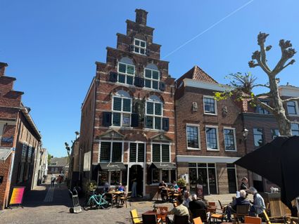 Historisch horecapand Grand Café Hex in Oudewater, Groene Hart. Monumentaal trapgevelpand aan de Markt met terras, bezoekers in de zon en karakteristieke gevels op een sfeervol historisch stadsplein.
