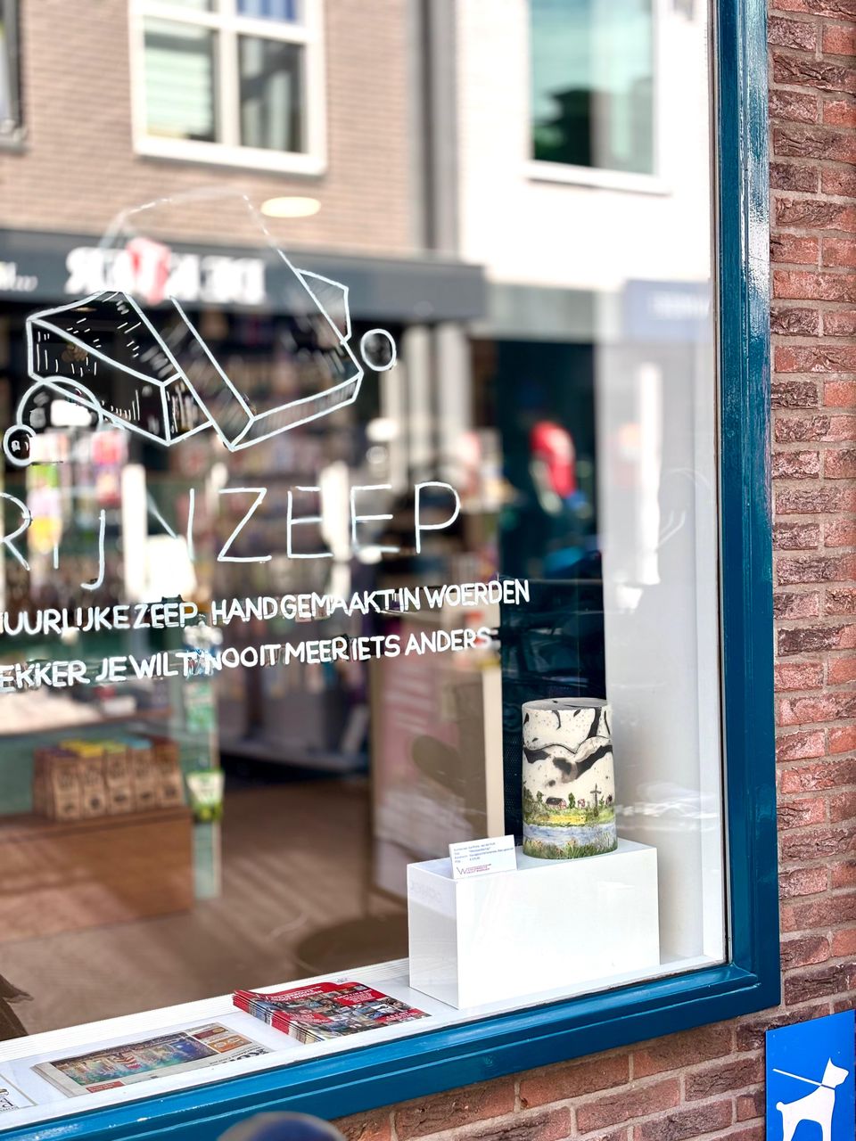 Winkelpand van RIJZEER in Woerden, Groene Hart, etalage met illustratie van zeep en tekst over handgemaakte natuurlijke zeep, met keramiekobject in het raam tijdens de Atelierroute Woerden.