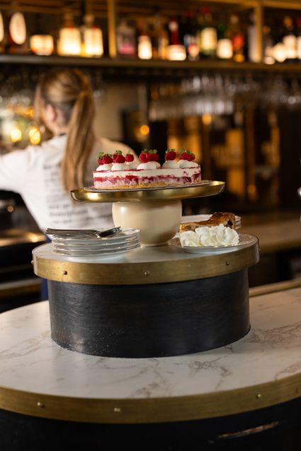 Restaurant Bistro de Bock in Woerden, Groene Hart, sfeervolle horecalocatie met stuk frambozentaart en slagroom op een serveertafel in een warme baromgeving.