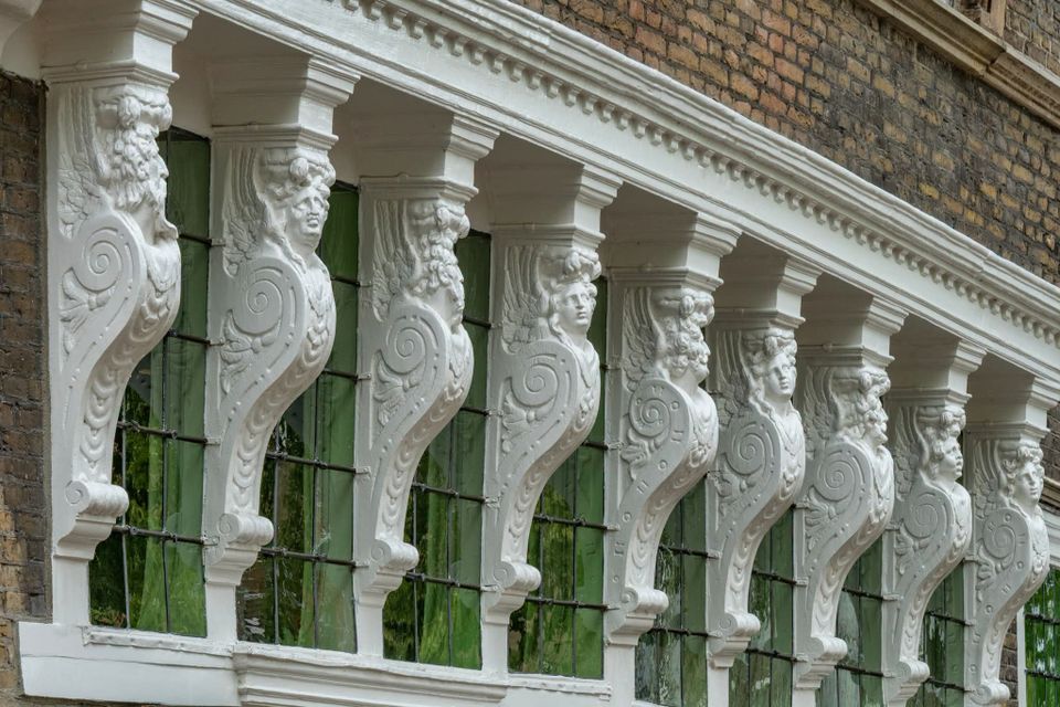 Historisch geveldetail, Oudewater, Groene Hart, sierlijke witte gevelconsoles met gebeeldhouwde figuren boven ramen van een monumentaal pand in de binnenstad.