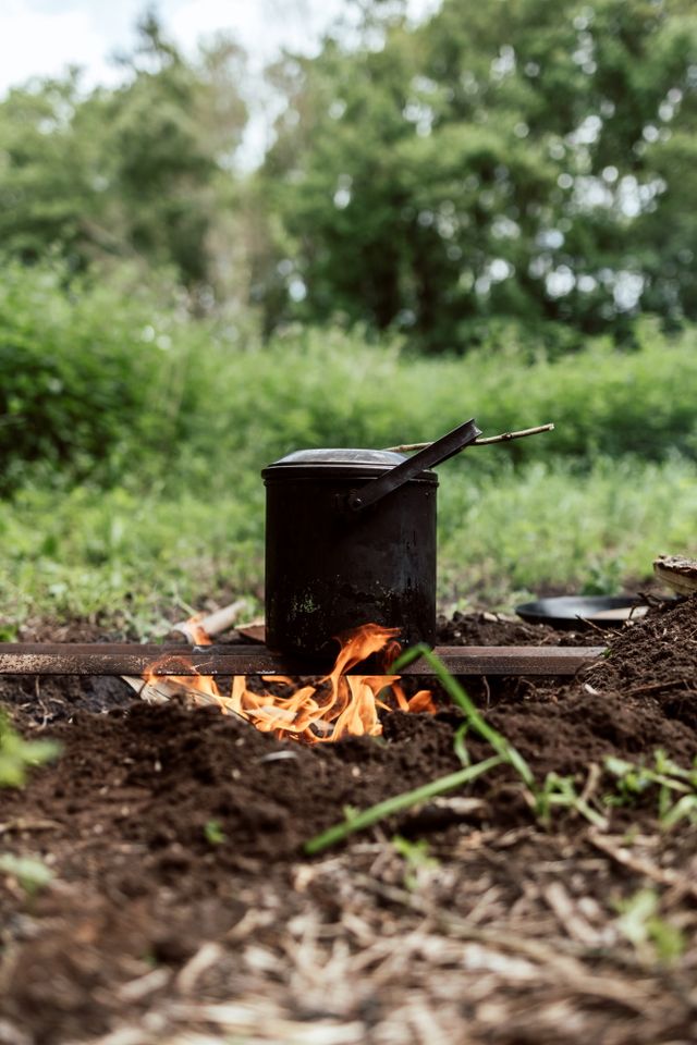 Ein geschlossener Topf steht auf einem Feuer in der Natur.