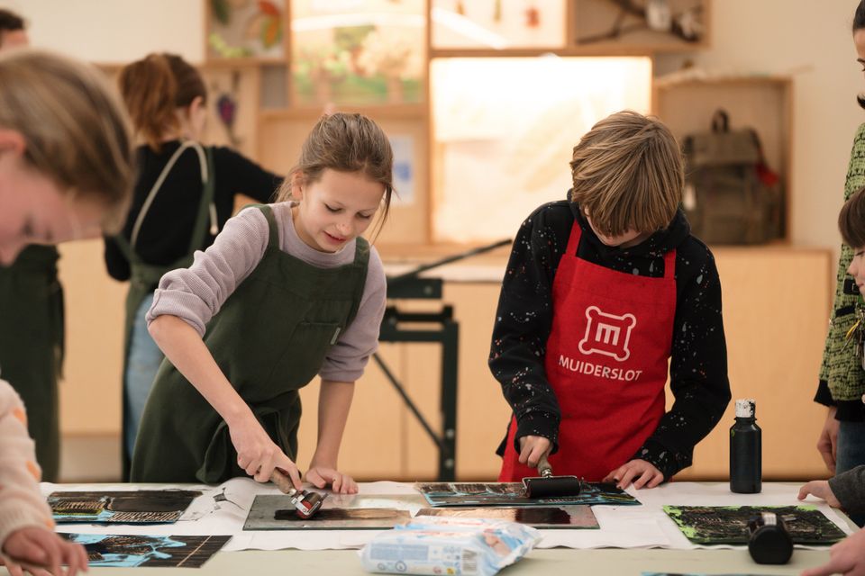 Twee kinderen knutselen in het kasteelatelier op het Muiderslot.