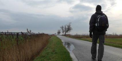 Man wandelt over een geasfalteerd pad tussen de oevers.