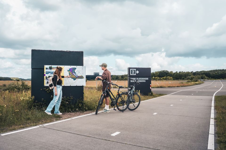 Een stel kijkt op de borden met informatie  over Park Vliegbasis Soesterberg. Een oude landingsbaan waar je nu overheen kan fietsen.