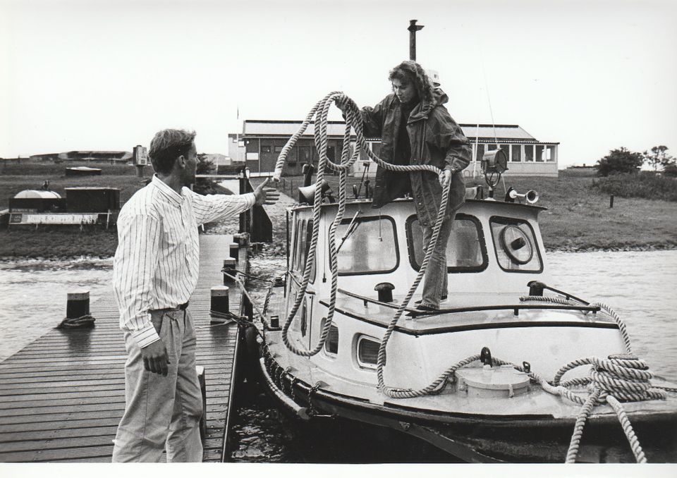 Een man en een vrouw meren hun boot aan op forteiland Pampus. (Zwart/wit)