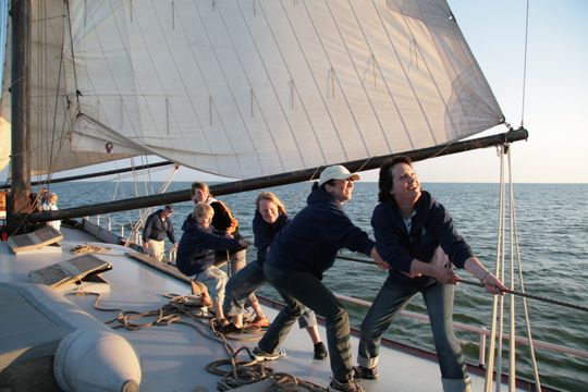 Groep mensen op zeilboot trekken aan touw.