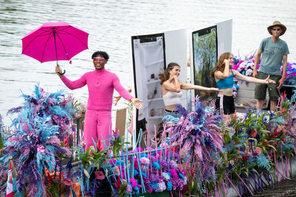 Kleurrijke boot vol bloemen met verkleedde mensen Varend Corso