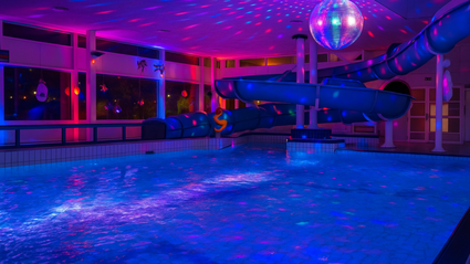 Overdekt zwembad Batenstein in Woerden, Groene Hart, binnenbad met waterglijbaan, discobal en kleurrijke verlichting tijdens evenement, sfeerbeeld van zwemmen en familie-uitje in recreatiebad.