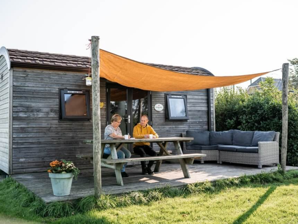 Mensen zittend voor een stacaravan bij Camping Hoeve Bouwlust in Delft