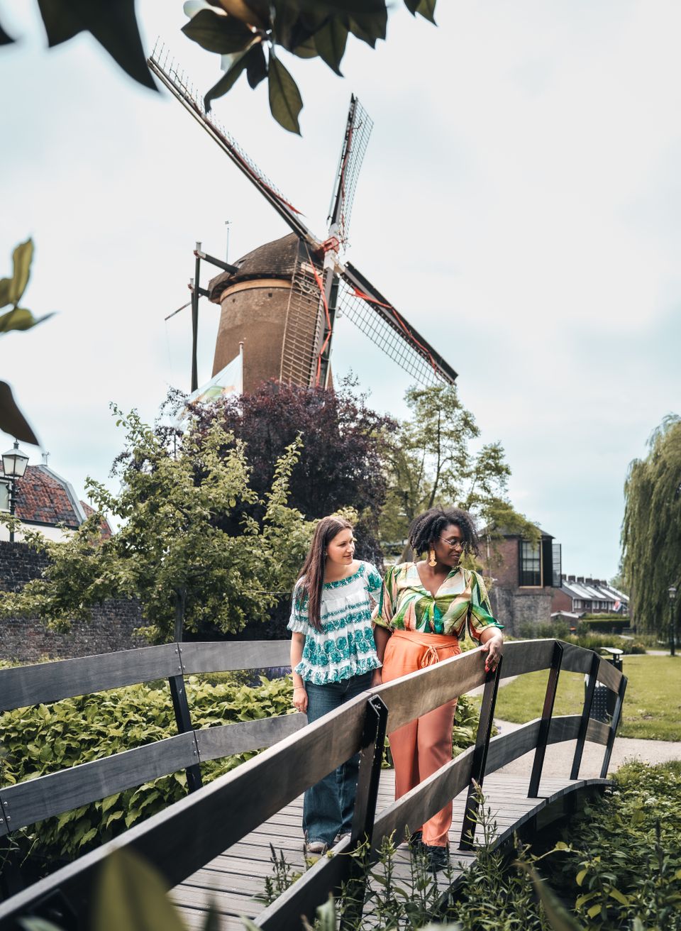 Korenmolen De Windotter in IJsselstein, Groene Hart. Wandelaars lopen over een houten brug met uitzicht op de historische stellingmolen, omringd door groen en de monumentale binnenstad.