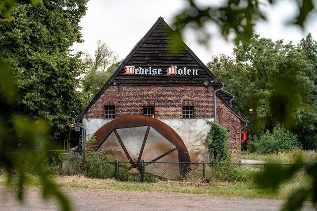 Zijaanzicht van de Wedelse Molen met het rad