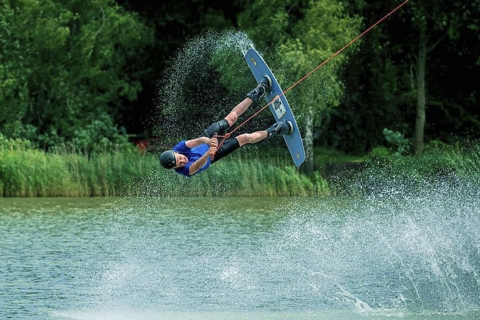 Een man maakt op een wakeboard een sprong op het water.