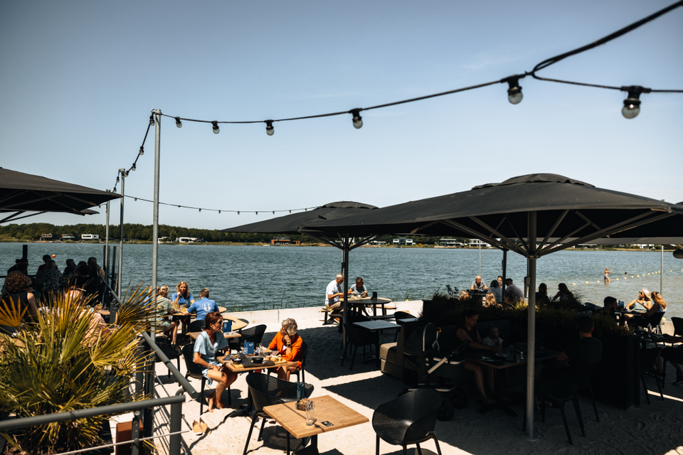Mensen op een terras, gelegen aan het water.