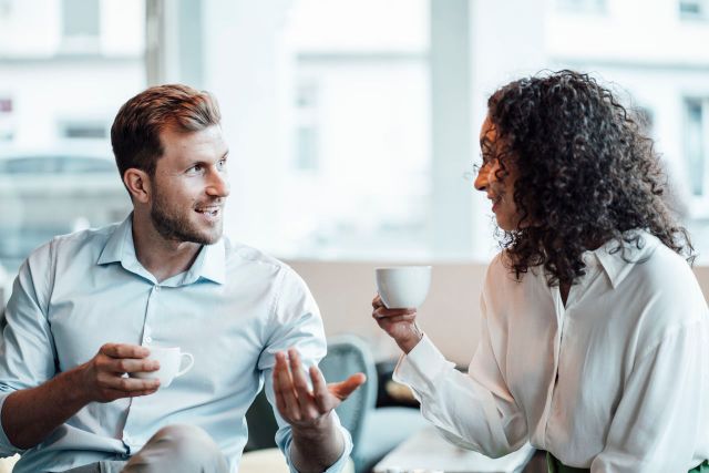 Twee personen zijn samen koffie aan het drinken en hebben een gesprek met elkaar.