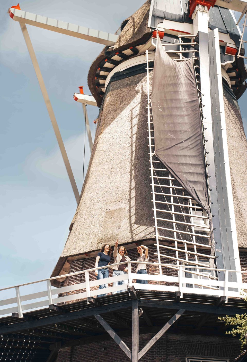 Korenmolen De Valk Montfoort, Groene Hart, bezoekers op de stelling van de historische windmolen met rieten romp en wieken, waar het traditionele molenaarsambacht van dichtbij wordt beleefd.