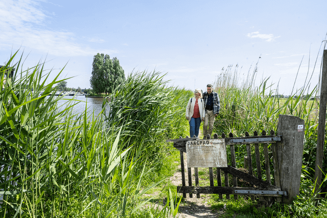 Man en vrouw wandelen het Jaagpad langs de Hollandse IJssel in het Groene Hart