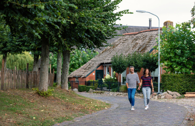 Een man en een vrouw wandelen door een brinkdorp.