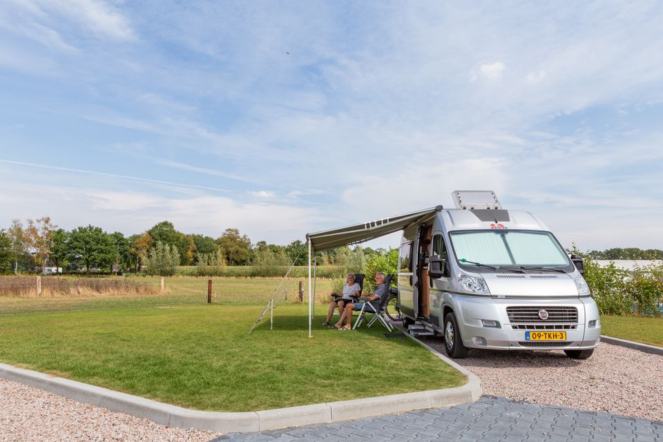 Camperplaats van De Gerrithoeve met een camper in de zon aan een groen grasveld.