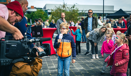 Jong kind met microfoon in de hand doet presentatie terwijl hij wordt gefilmd