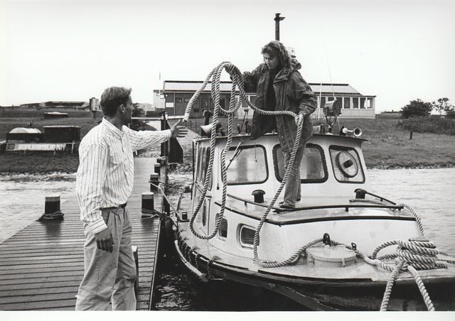 Een man en een vrouw meren hun boot aan op forteiland Pampus. (Zwart/wit)